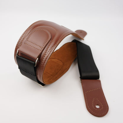 A brown leather guitar strap with a black webbing section and silver metal buckle, shown on a clean white background.