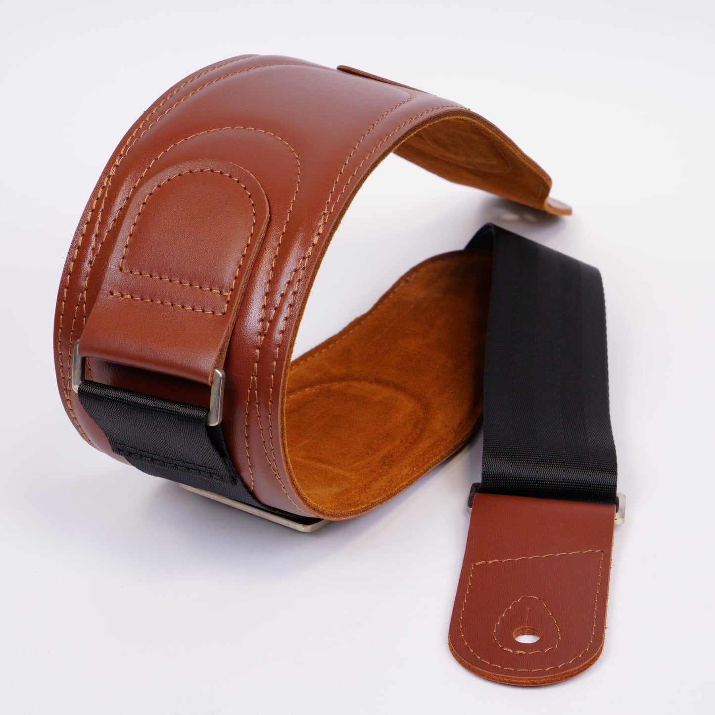 A brown leather guitar strap with a black webbing section and silver metal buckle, displayed on a clean white background.