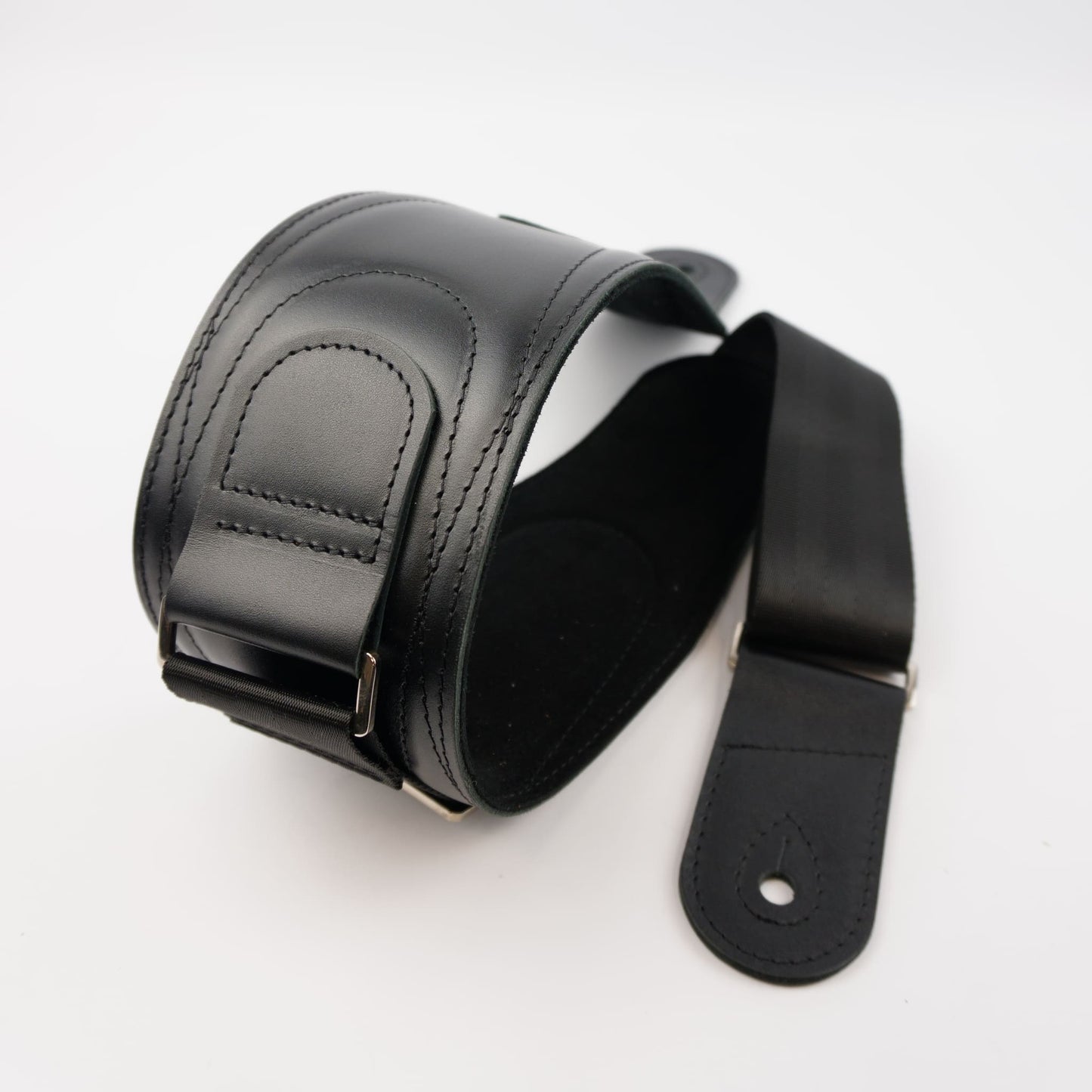 A black leather guitar strap with silver metal hardware, shown on a plain white background.