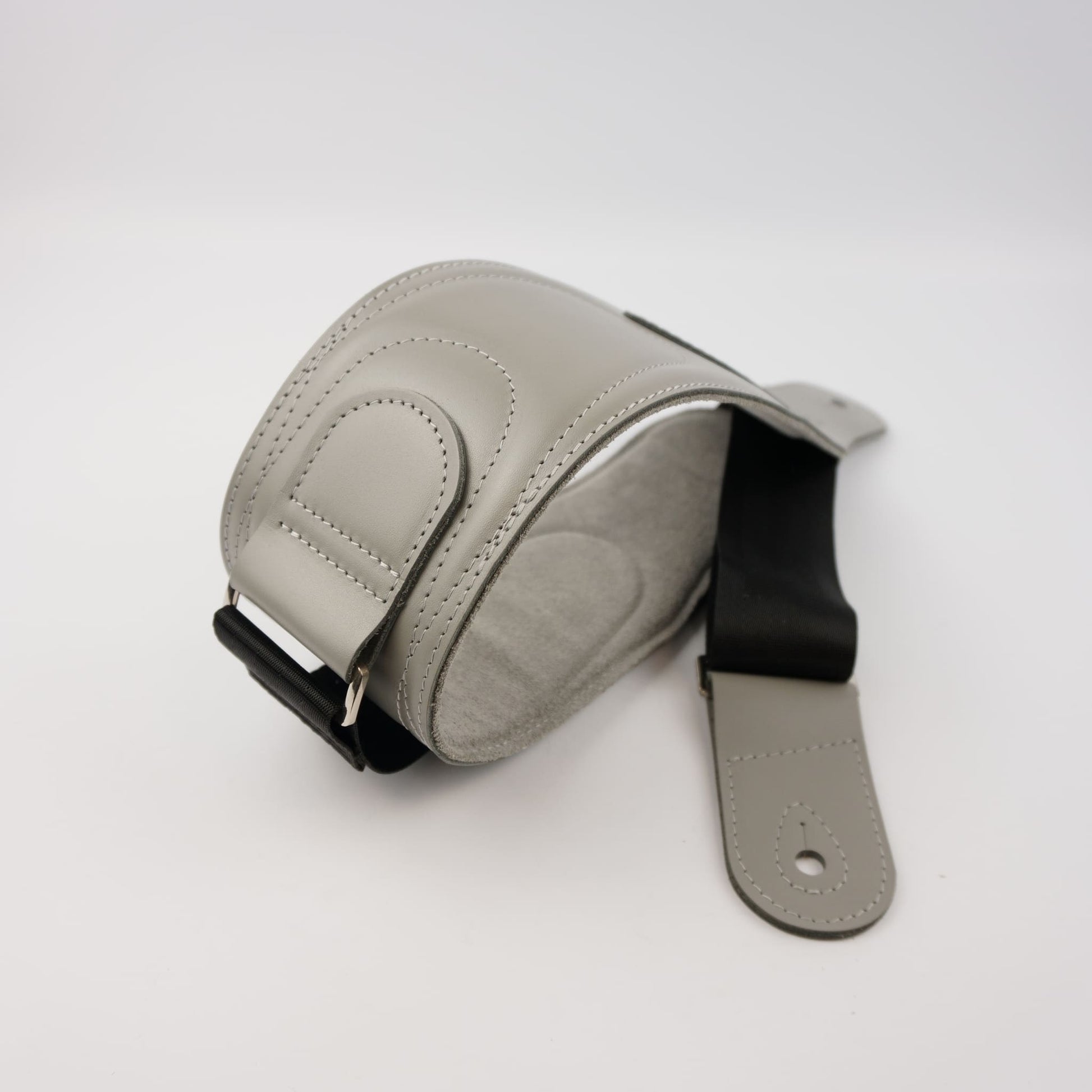 A light gray leather guitar strap with a black webbing, shown on a clean white background.