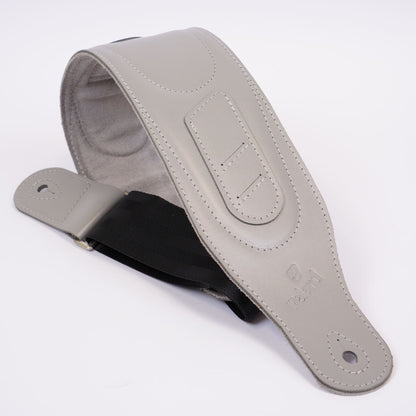 A light gray leather guitar strap with a black inner lining and a black adjustable webbing loop, displayed on a clean white background.