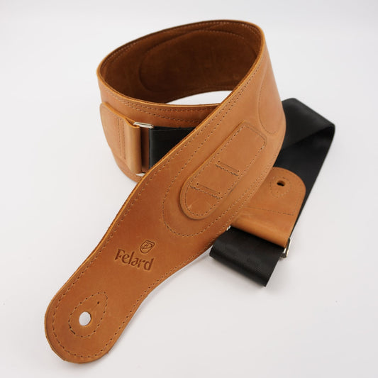A tan leather guitar strap with a black rubber section and silver metal buckle, featuring the 'Felard' brand name and logo on the leather end, shot on a white background.